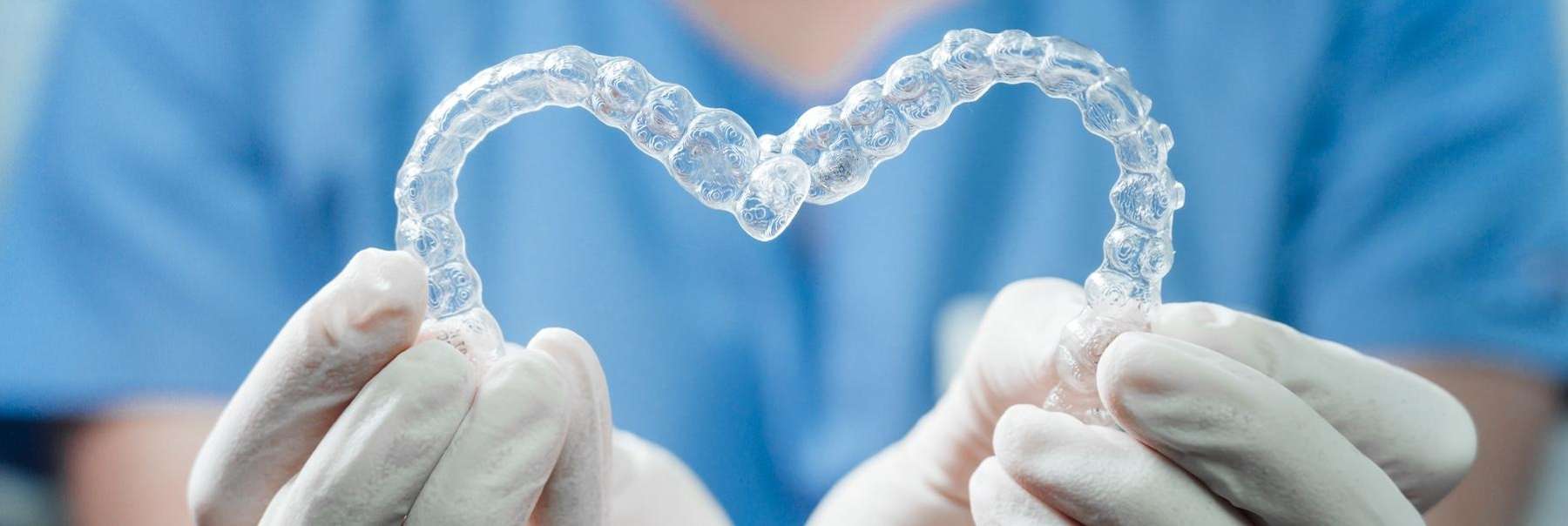 A dentist holding Invisalign trays in the shape of a heart | Langhorne dentist