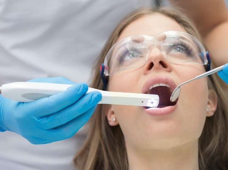 A dentist using an intraoral camera on a patient